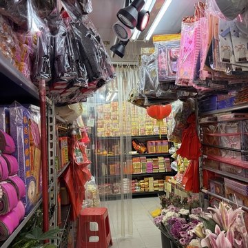 由舖入面望出門口,兩邊貨架由地下掛到天花,擺滿紙衣、衣紙同金銀,門口一邊擺住鮮花