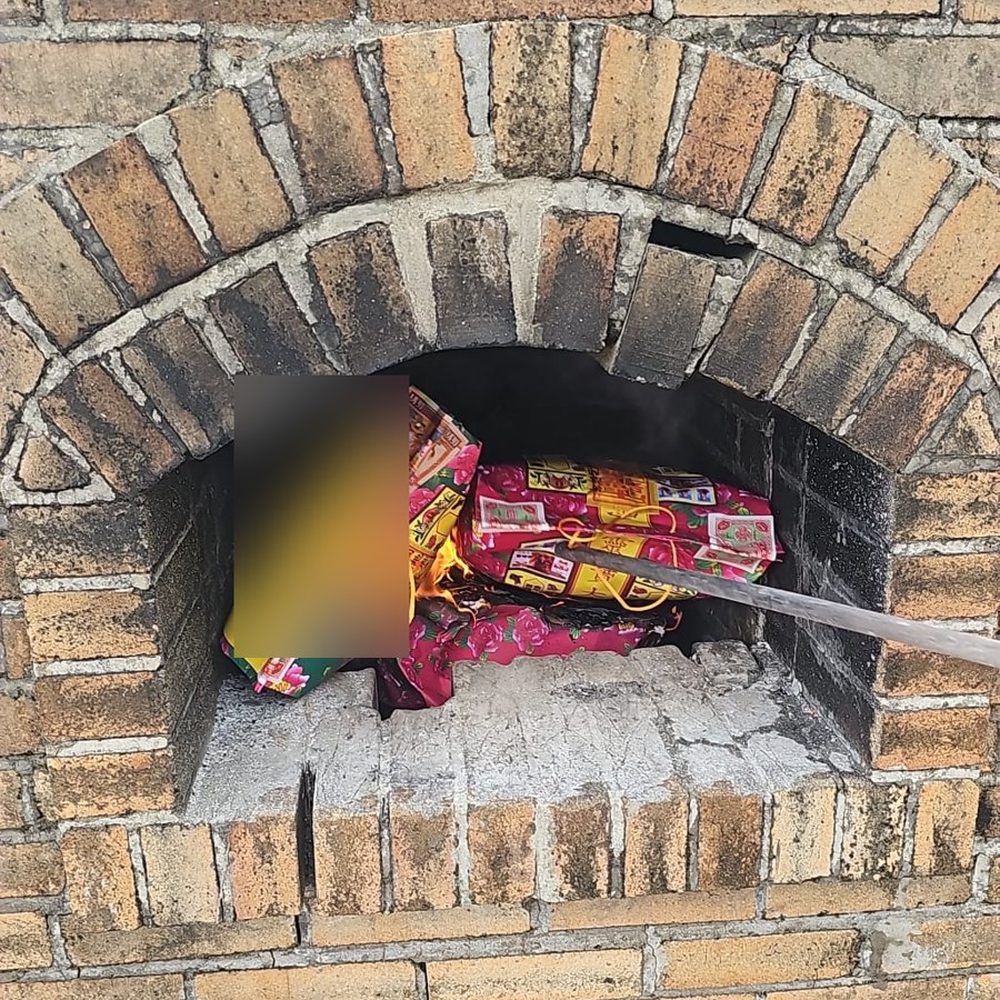 化寶爐爐口入面燒緊嘅一批衣包,見到火同磚牆;袋面寫住嘅字已經打格仔遮住