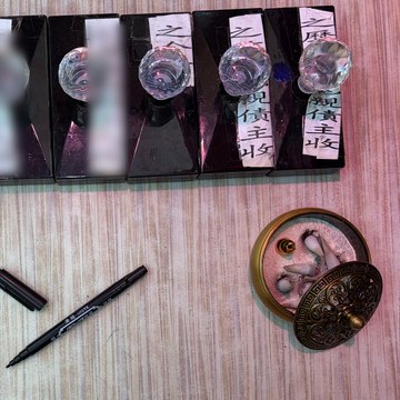 寫包枱:一支開咗蓋嘅黑色筆擺喺枱面,上面一排用水晶玻璃座壓住嘅手寫紙條,右邊兩張寫住「冤親債主收」,旁邊一個燃過香嘅銅香爐。左邊兩張同呢個服務無關嘅紙條已經遮咗